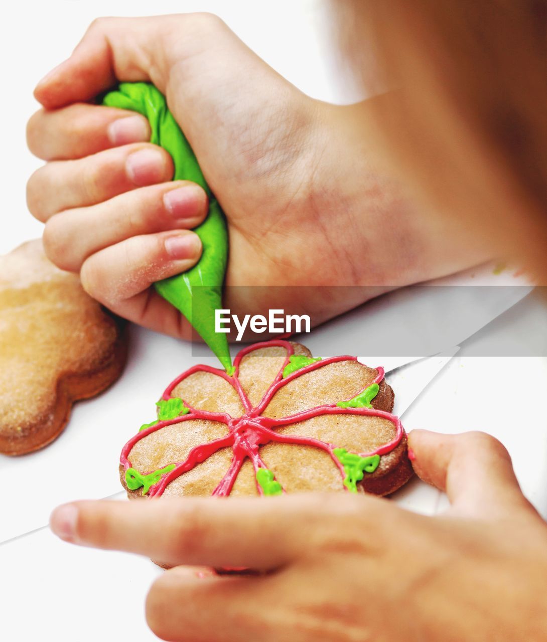 Hands of woman holding cookie and decorating it