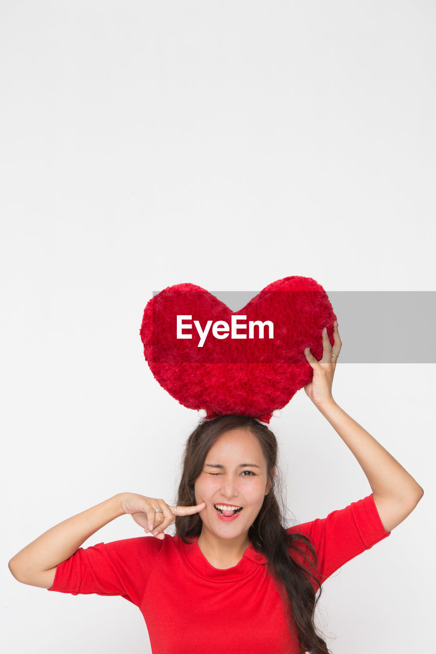 emotion, positive emotion, red, happiness, heart shape, smiling, one person, studio shot, valentine's day, women, portrait, indoors, love, white background, cheerful, pink, clothing, adult, young adult, joy, copy space, fun, celebration, cut out, heart, looking at camera, female, waist up, front view, carefree, smile, hairstyle, teeth, holding, enjoyment, brown hair, long hair, laughing, person, excitement, cute, lifestyles, event, holiday, facial expression