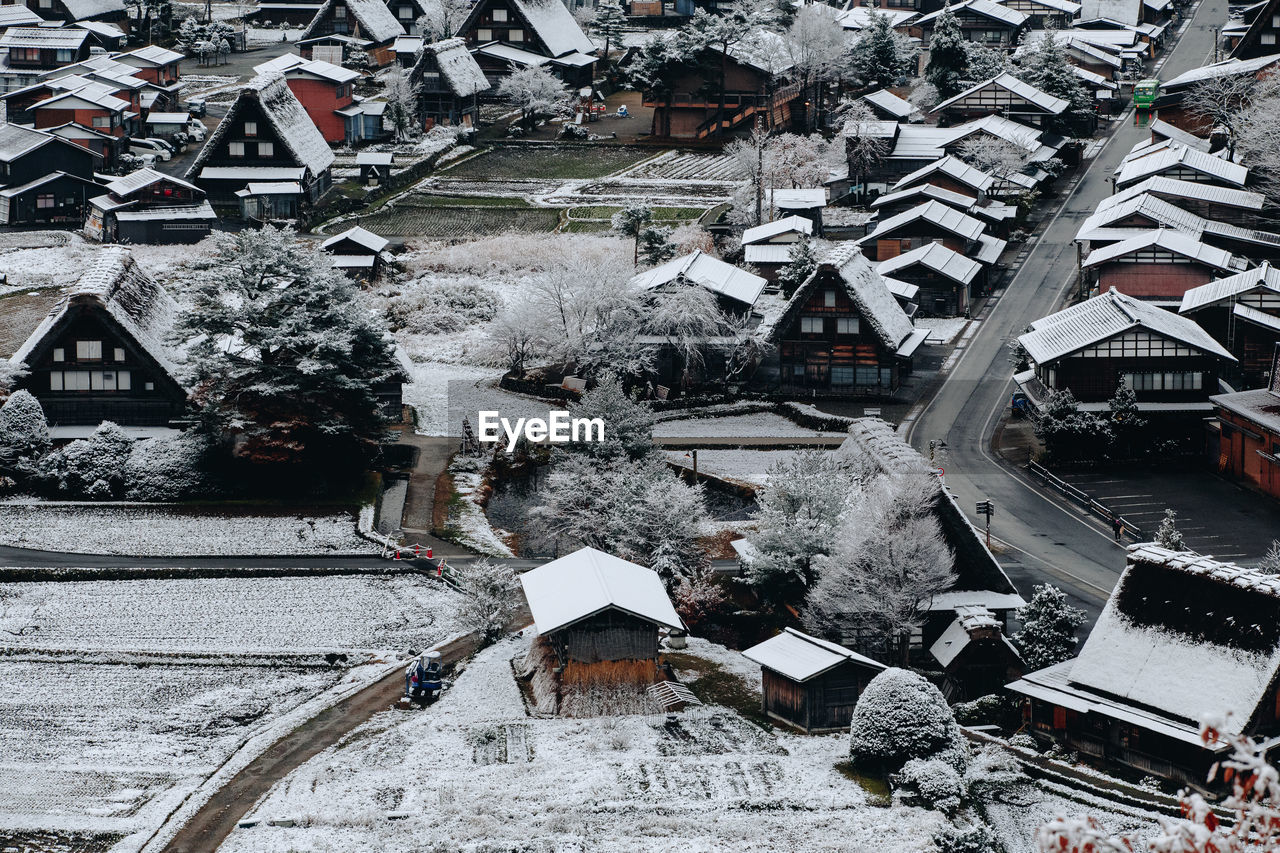 HIGH ANGLE VIEW OF SNOW COVERED HOUSES BY BUILDINGS