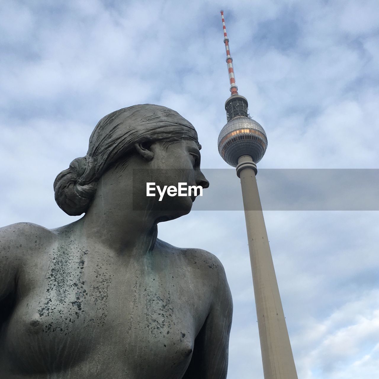 Low angle view of statue and fernsehturm tower against sky