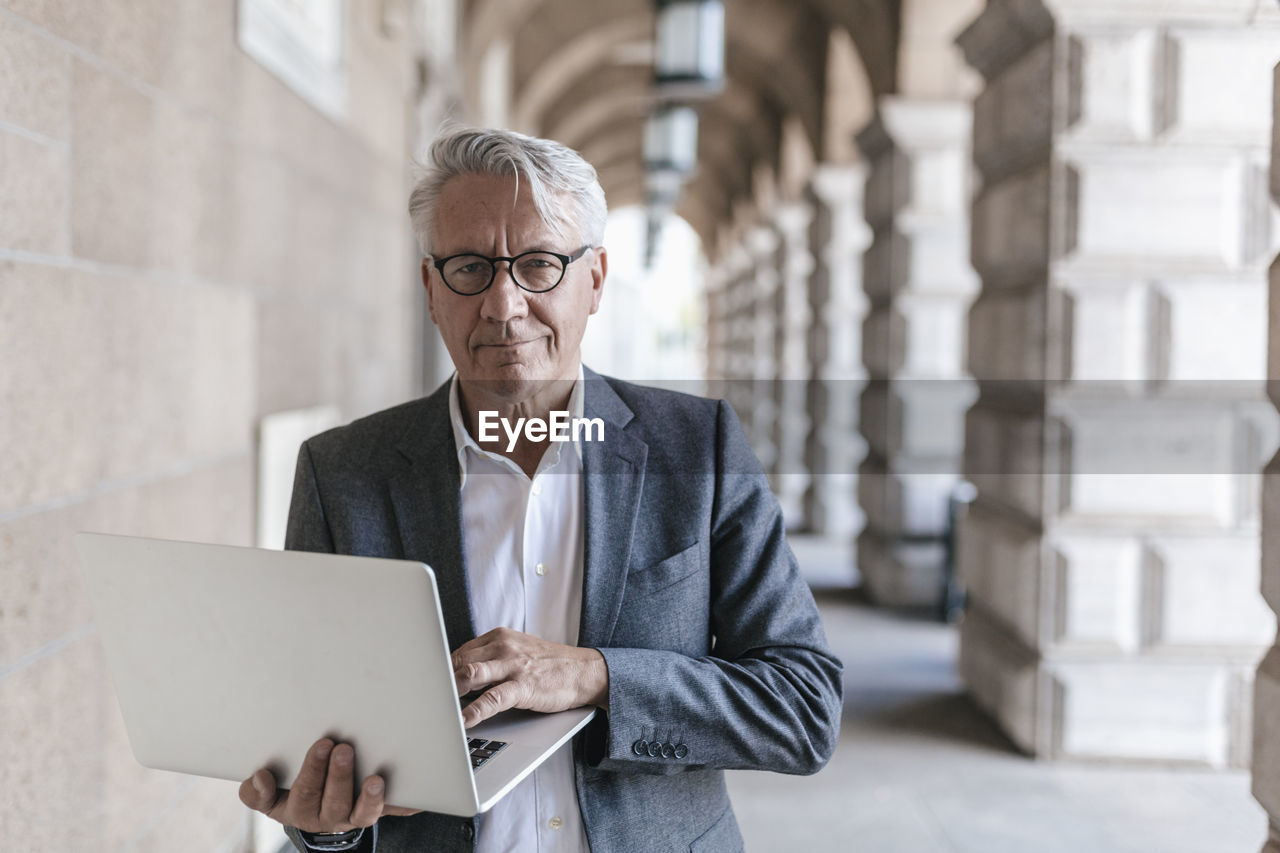 Portrait of senior businessman holding laptop