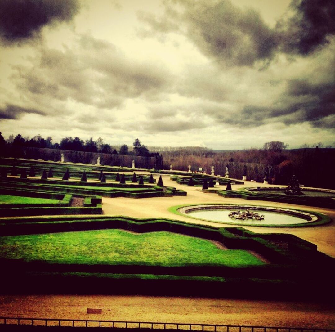 Scenic view of park against cloudy sky