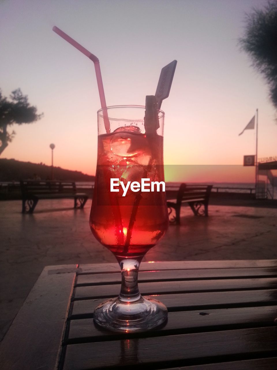 WINEGLASS ON TABLE AGAINST SKY IN CITY DURING SUNSET