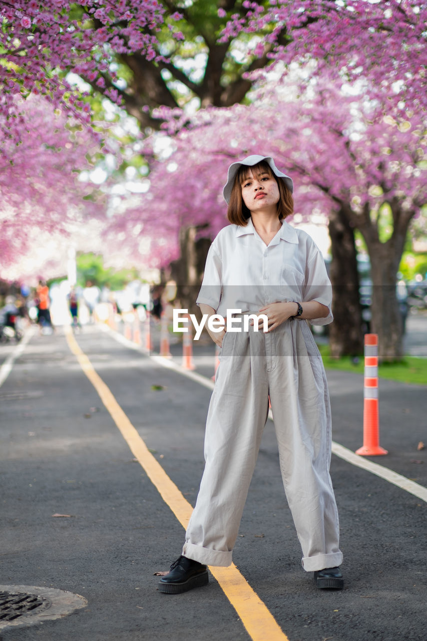 Portrait of young woman standing on road in city