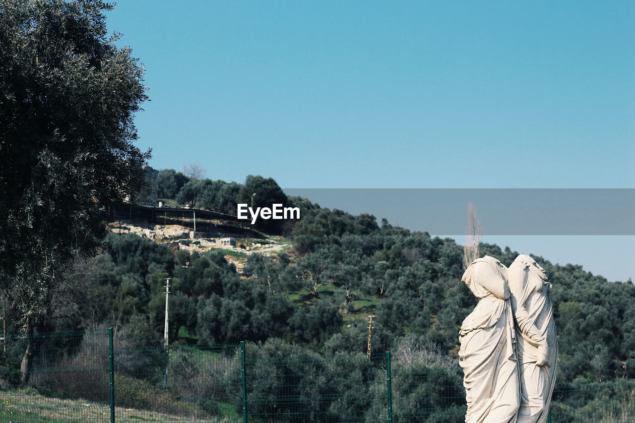 Statue by trees against clear sky