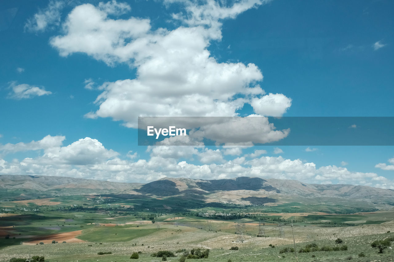 environment, landscape, scenics - nature, sky, cloud, beauty in nature, mountain, nature, plain, land, grassland, horizon, tranquility, tranquil scene, non-urban scene, travel destinations, travel, no people, blue, mountain range, field, day, plant, tourism, rural scene, plateau, outdoors, grass, rural area, idyllic, green, semi-arid, remote, valley, meadow, prairie, cloudscape, social issues, dramatic landscape, awe, agriculture, horizon over land, rock