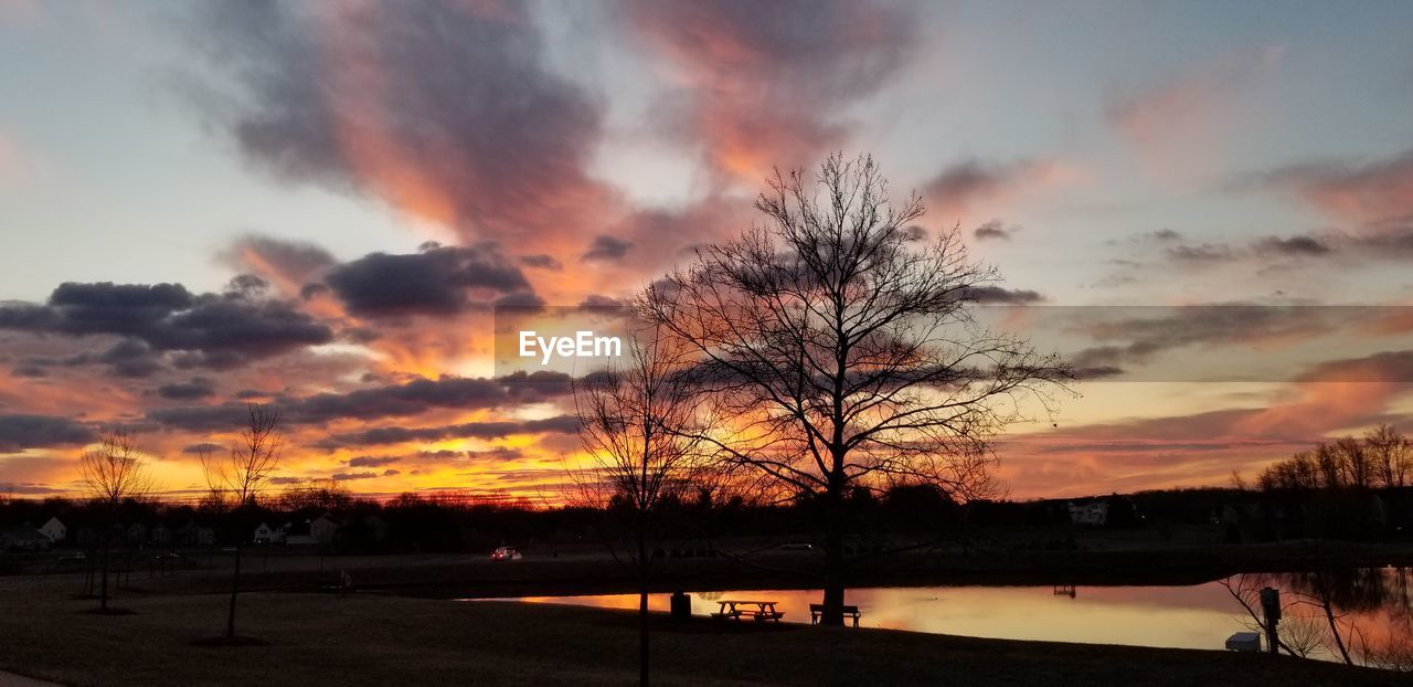 SILHOUETTE BARE TREES BY LAKE AGAINST ROMANTIC SKY