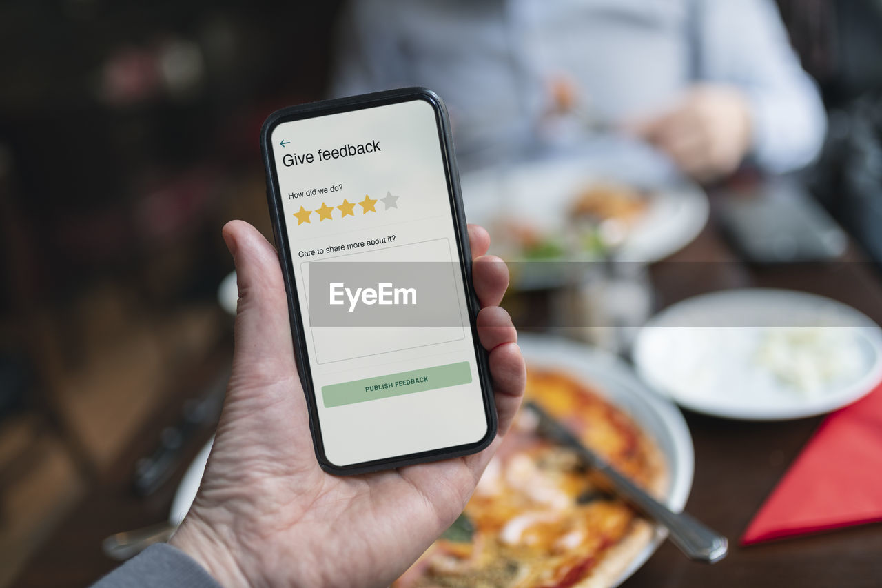 Person holding smart phone with restaurant rating app