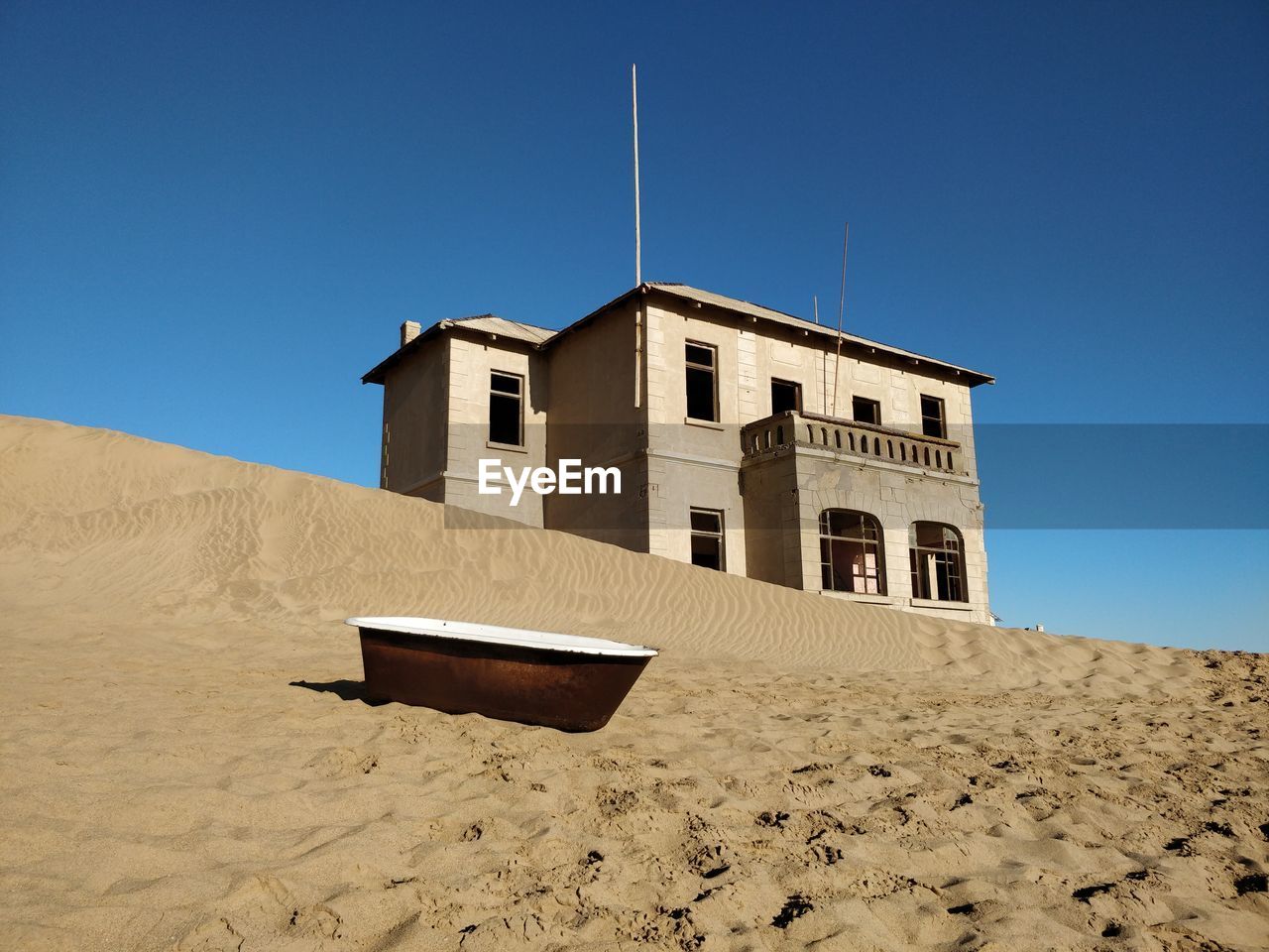 LOW ANGLE VIEW OF BUILDING ON BEACH AGAINST CLEAR SKY