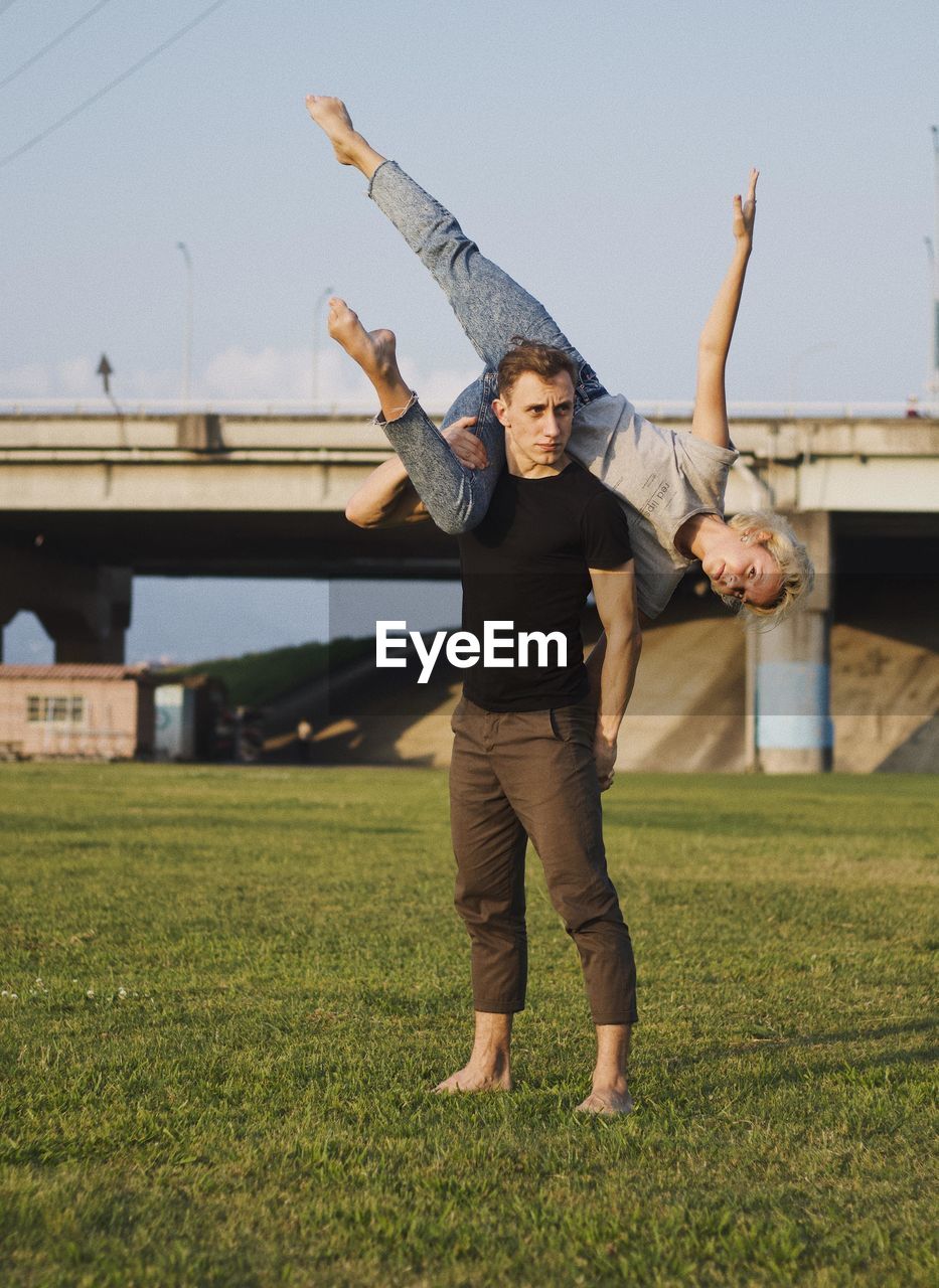 Full length of young man lifting woman while standing on field