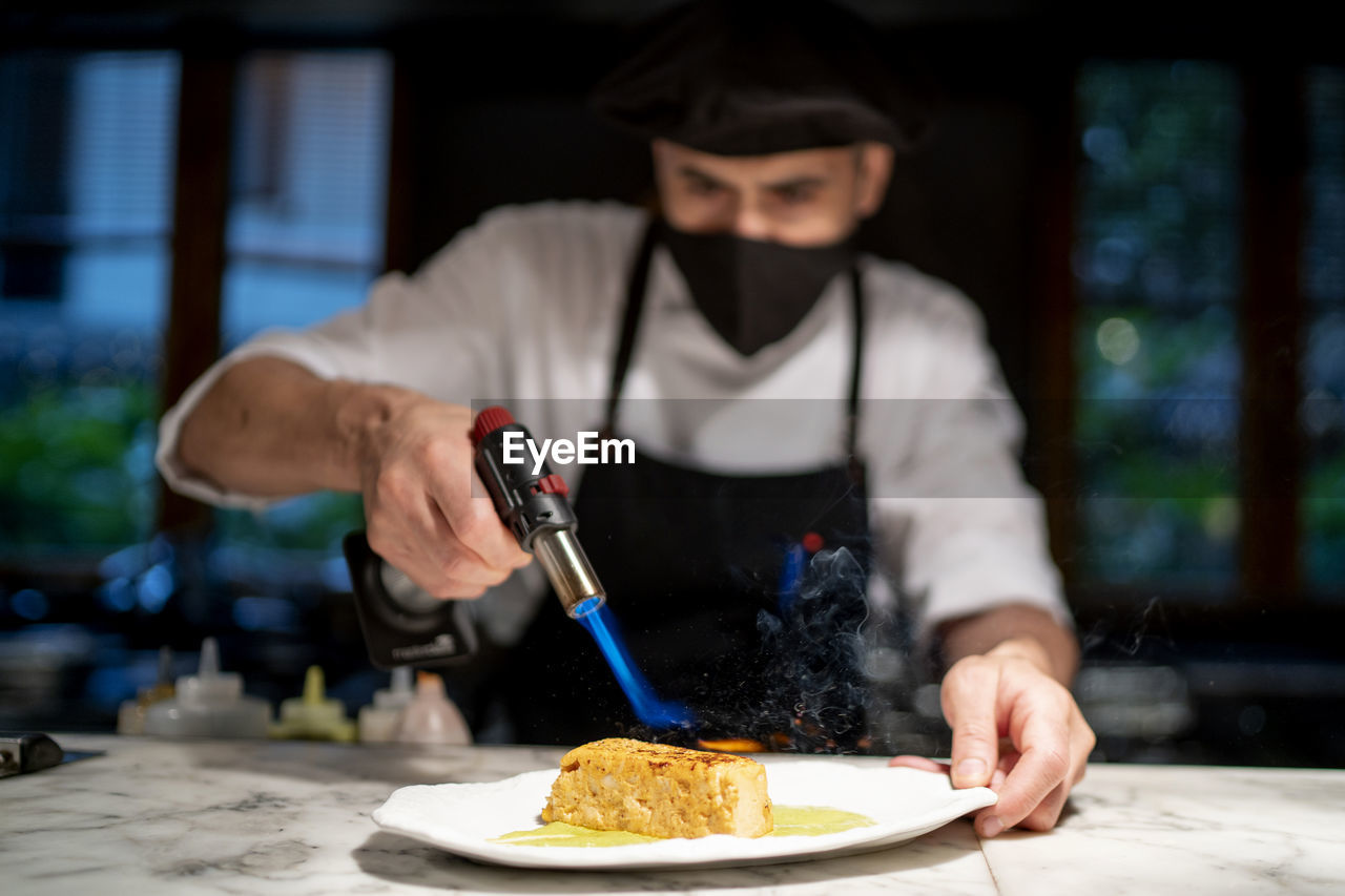 Chef preparing pudding while giving flame in restaurant kitchen