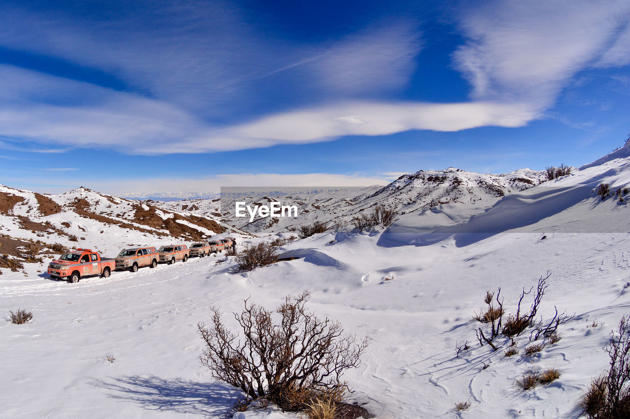 Scenic view of snowcapped mountains against cloudy blue sky on sunny day