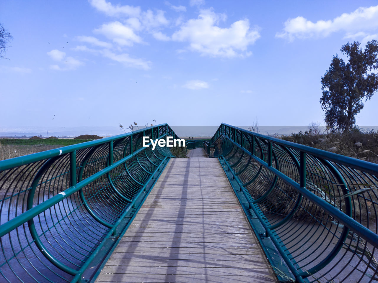 sky, cloud, blue, nature, the way forward, architecture, bridge, no people, walkway, water, footpath, land, diminishing perspective, built structure, outdoors, day, travel destinations, railing, travel, tree, transportation, footbridge, landscape, environment, plant, scenics - nature, tourism, sea, tranquility, vanishing point, beauty in nature