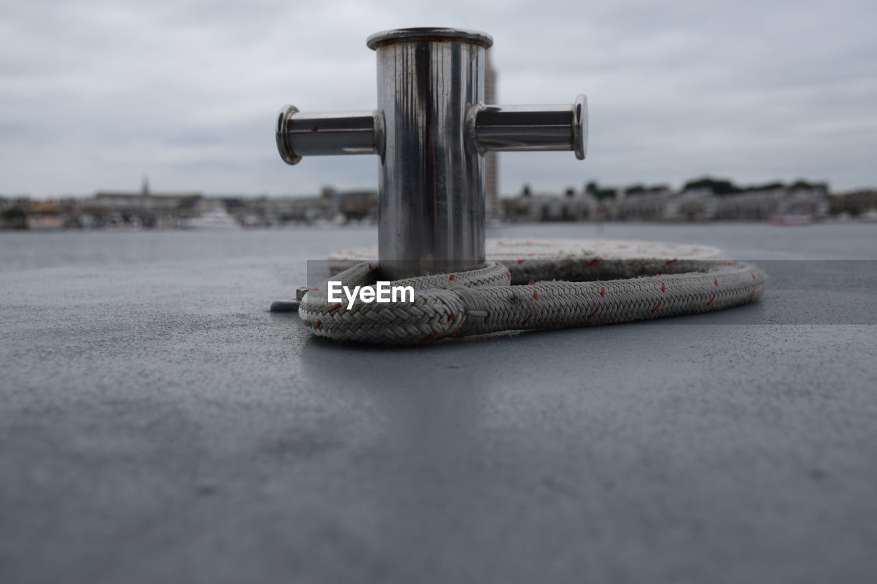 Close-up of pole with rope against sky