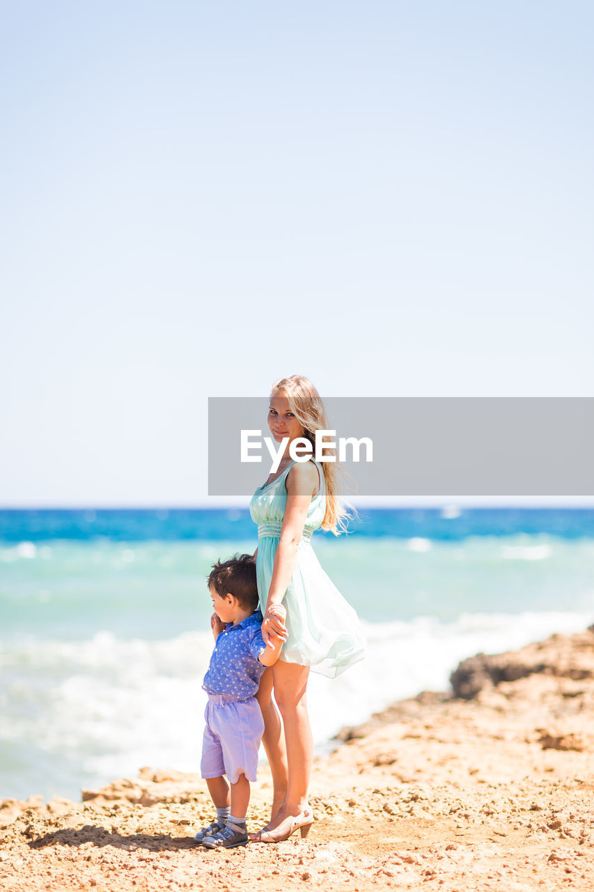 FULL LENGTH OF WOMAN ON BEACH AGAINST SEA