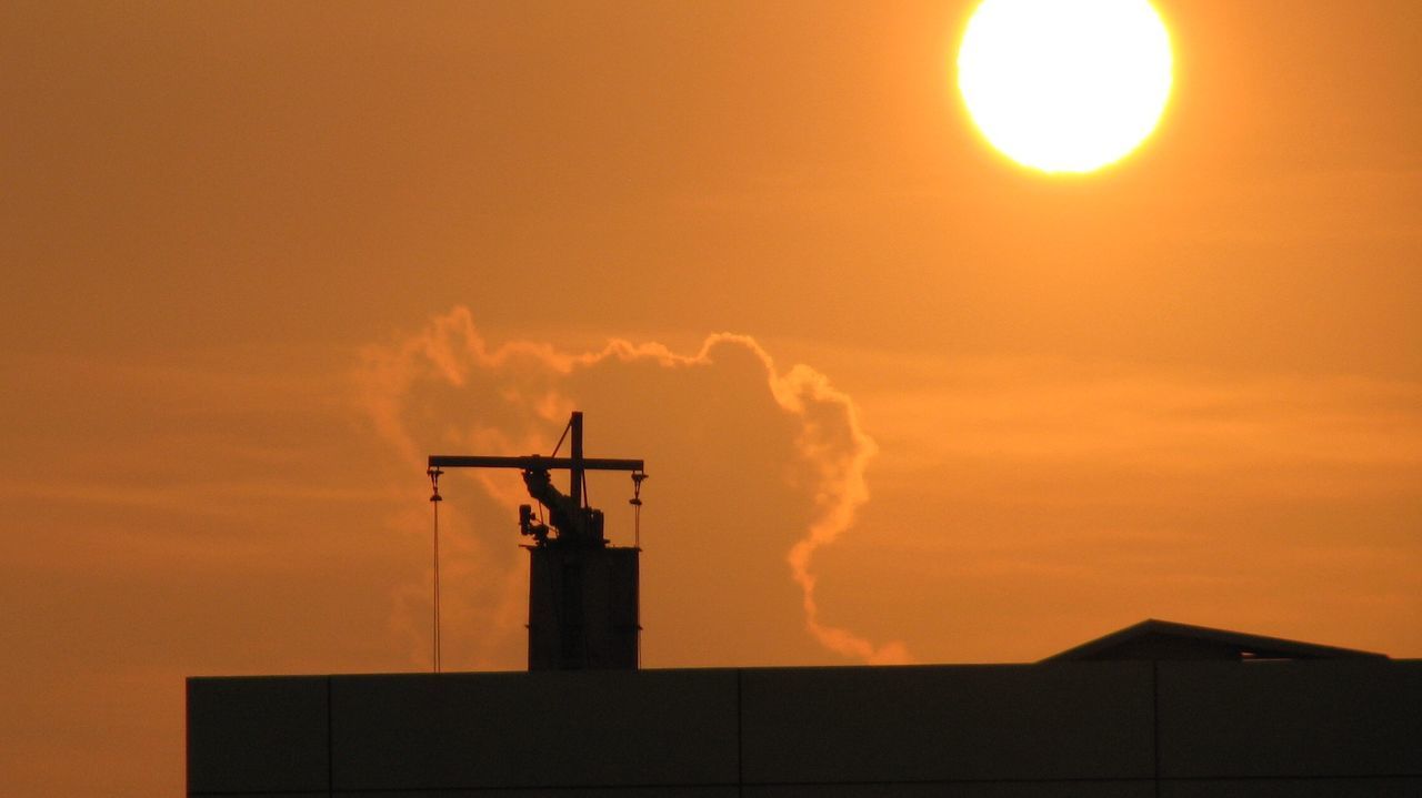 Low angle view of silhouette building against orange sky