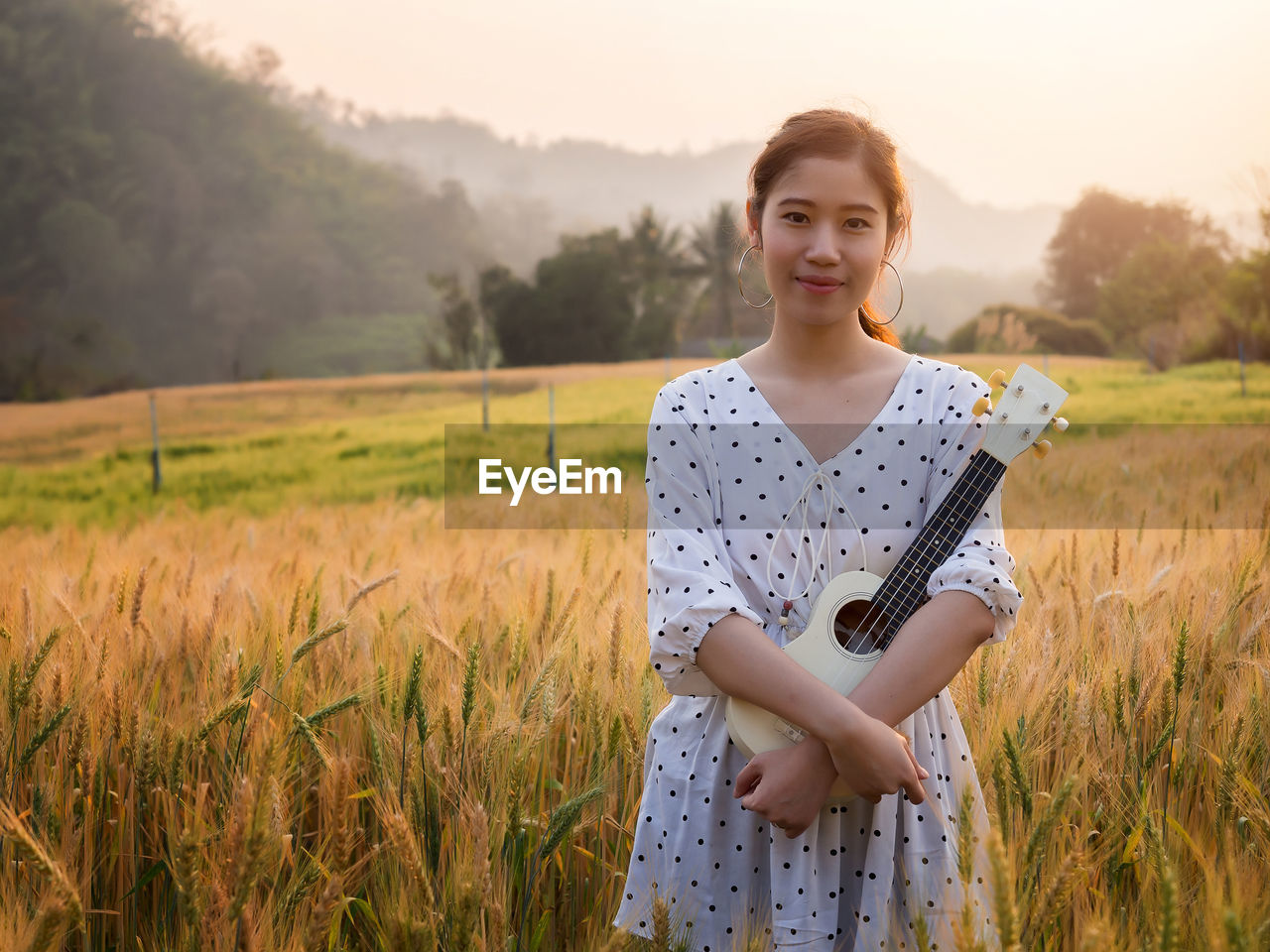 portrait of young woman standing on field against sky