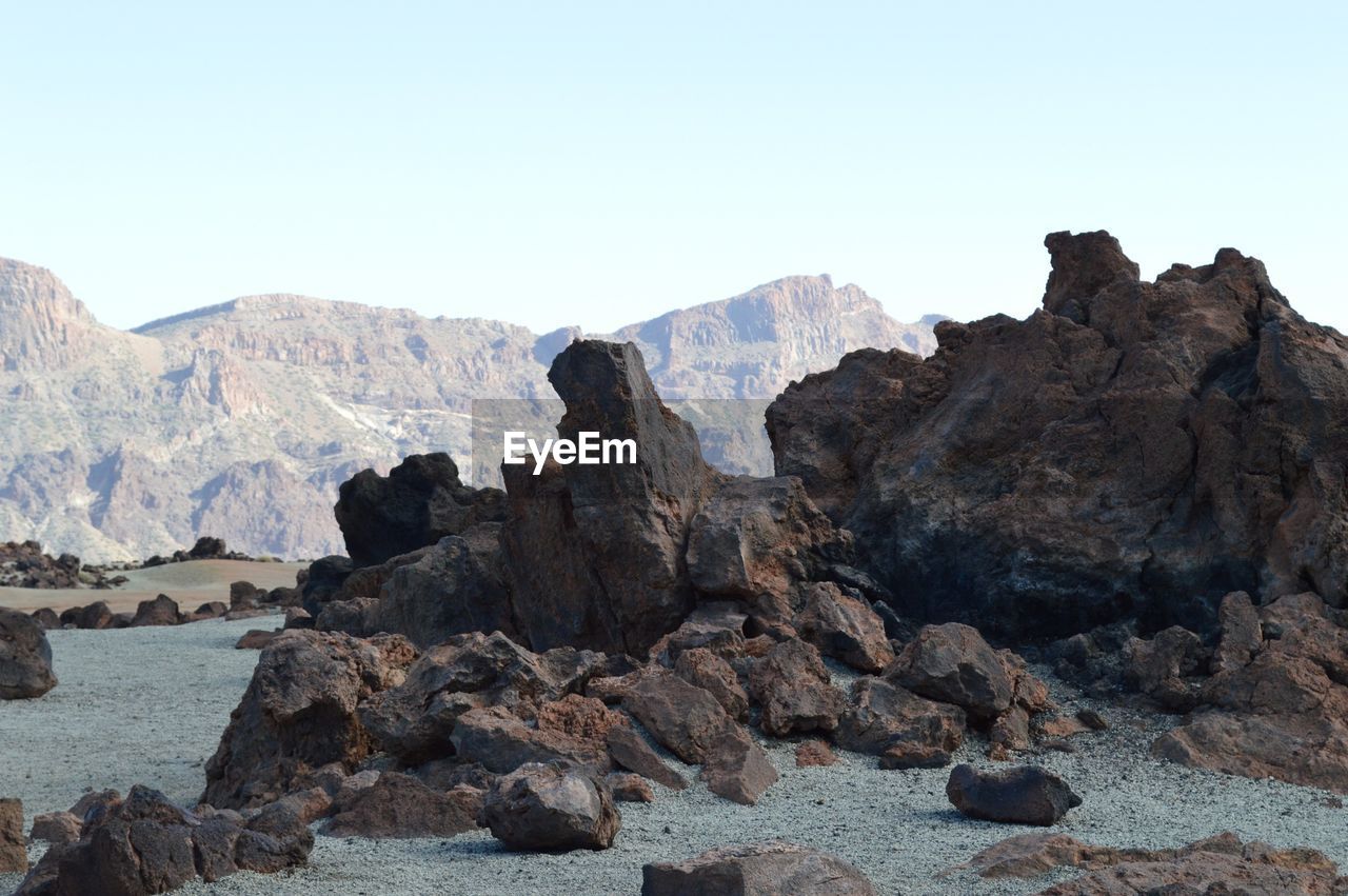 Rock formations on field against clear sky