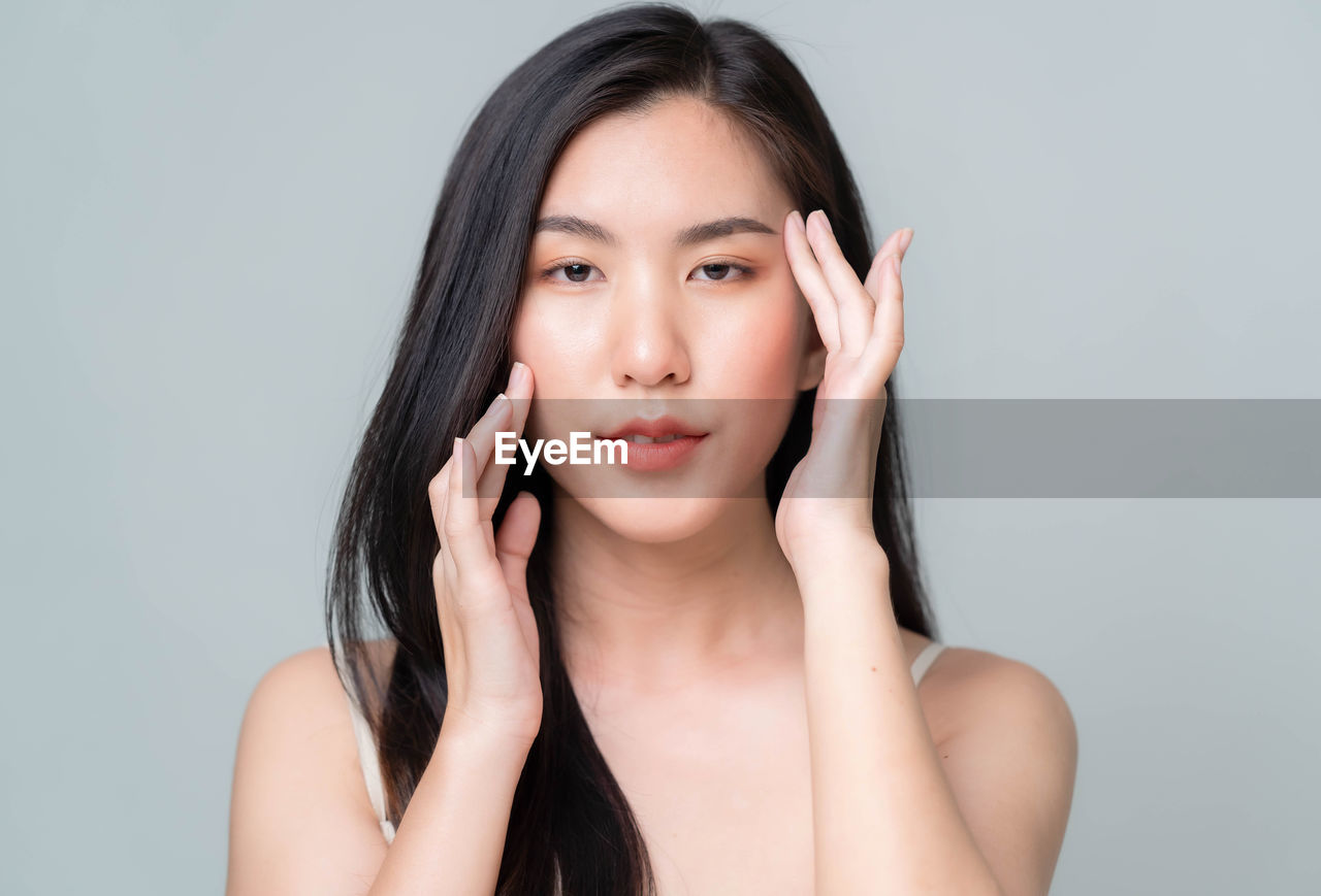 PORTRAIT OF BEAUTIFUL WOMAN AGAINST WHITE BACKGROUND