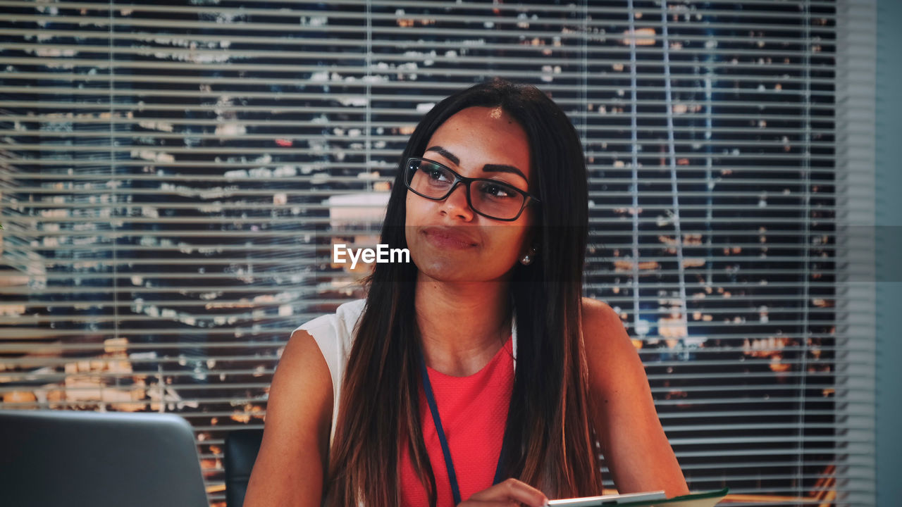 Young woman looking away while sitting at office