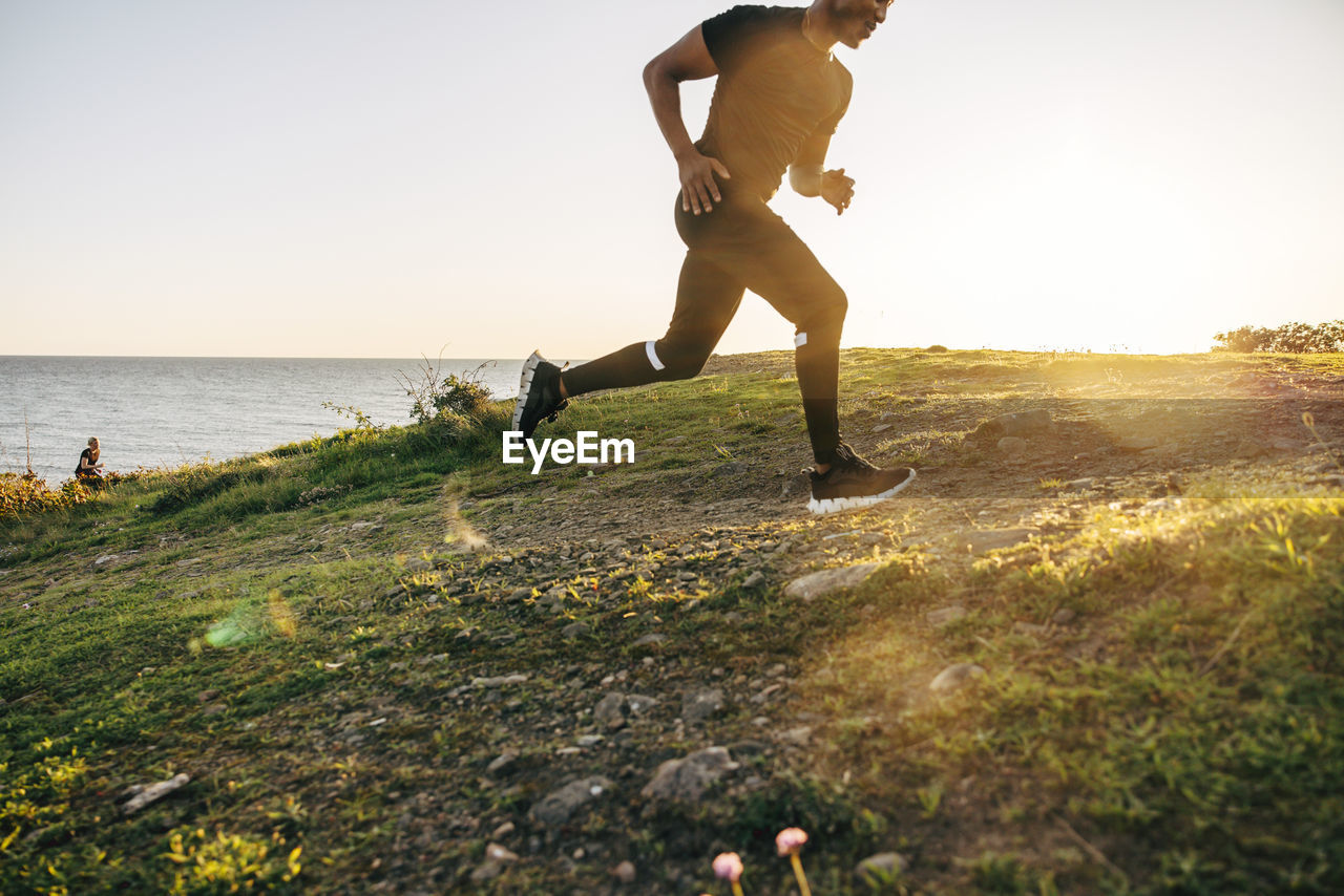 Young man running on hill near sea