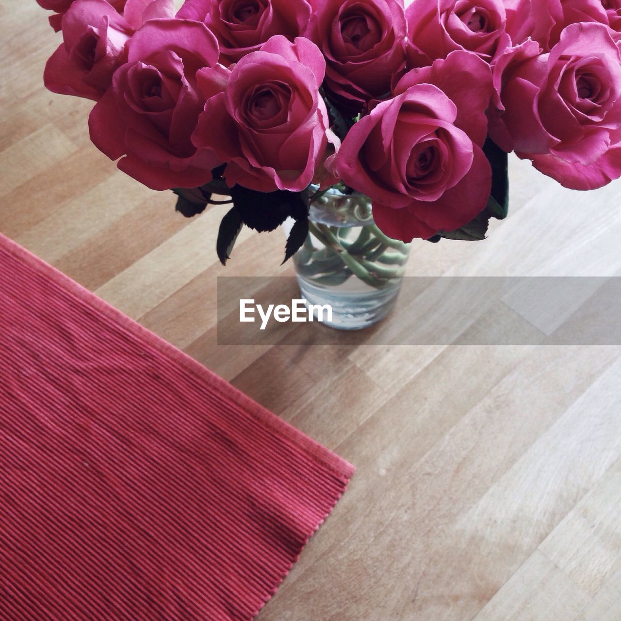 High angle view of pink roses in vase by place mat on table