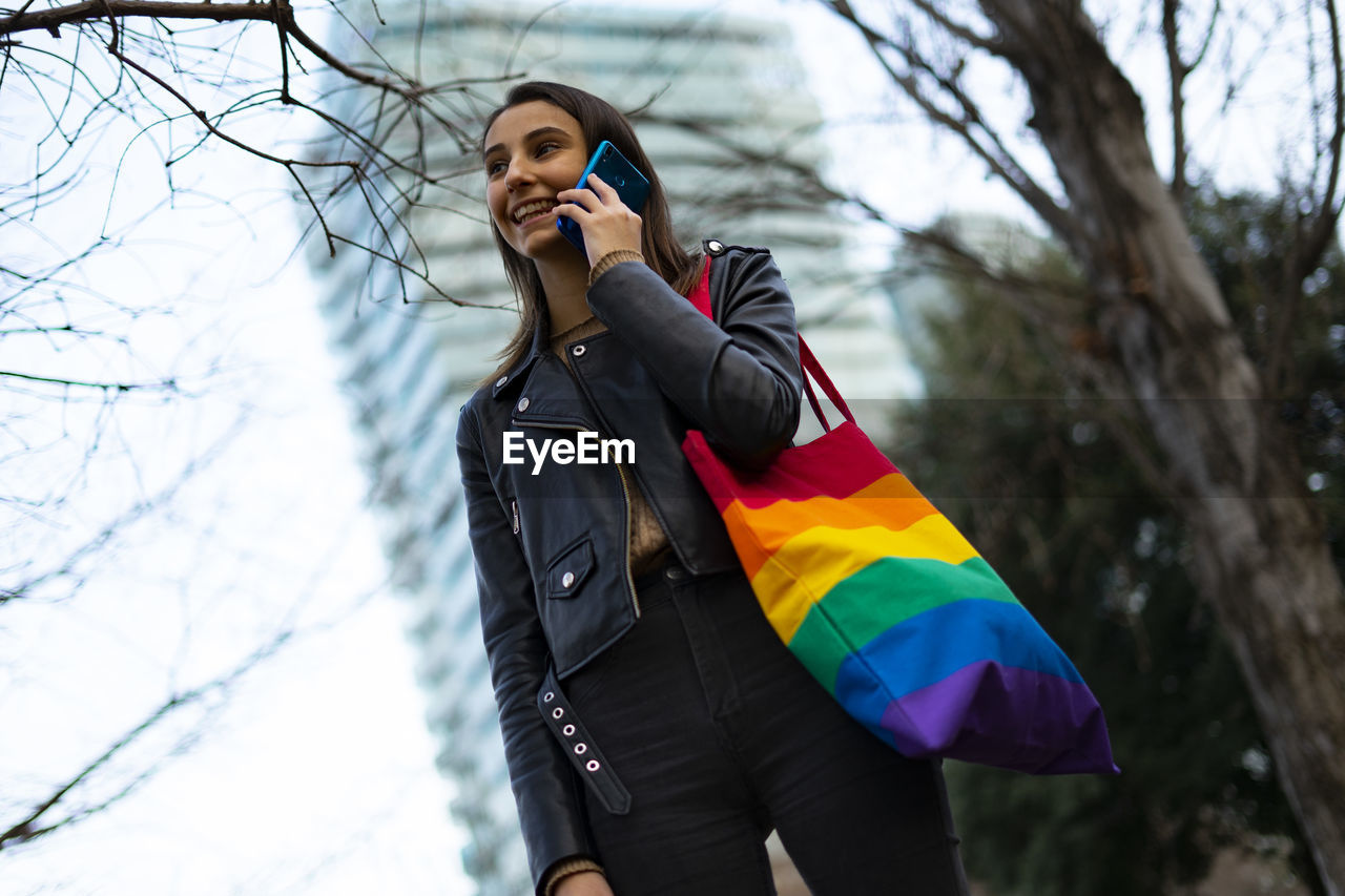 Beautiful lesbian woman with a pride bag talking on the phone.