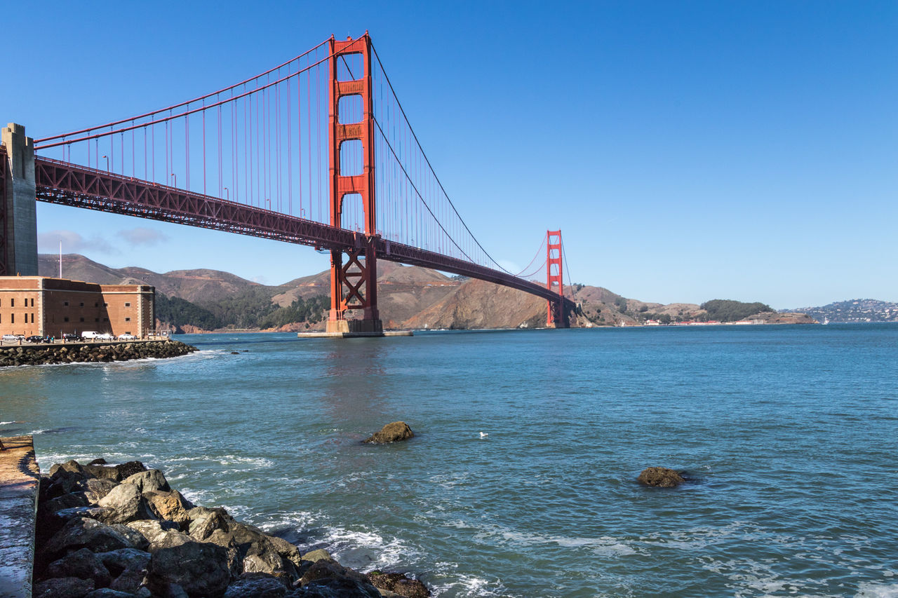 Low angle view of golden gate bridge over sea against clear blue sky
