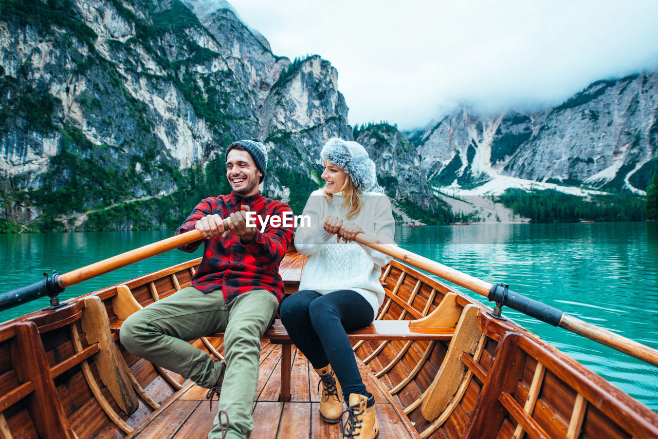 WOMAN SITTING ON LAKE AGAINST MOUNTAIN