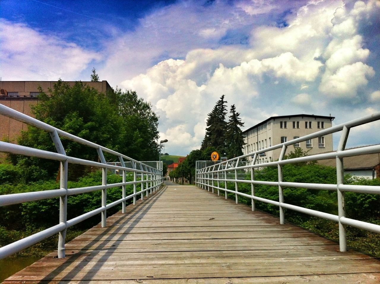 WALKWAY LEADING TOWARDS BUILDING AGAINST CLOUDY SKY