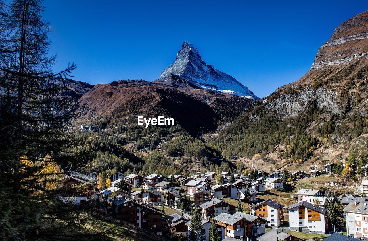 Aerial view of townscape and mountains against clear blue sky