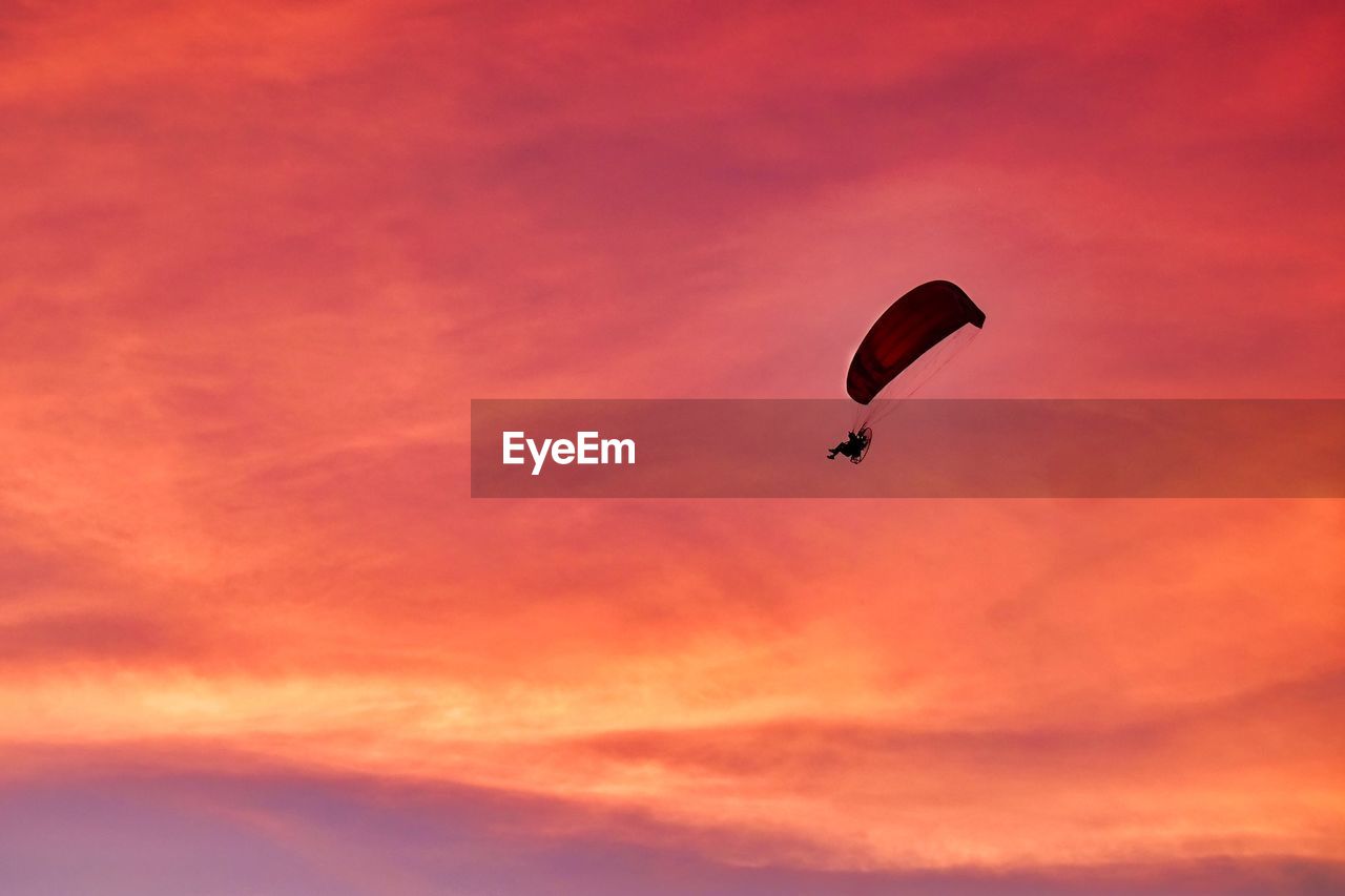 Silhouette of person paragliding under a beautiful florida sunset