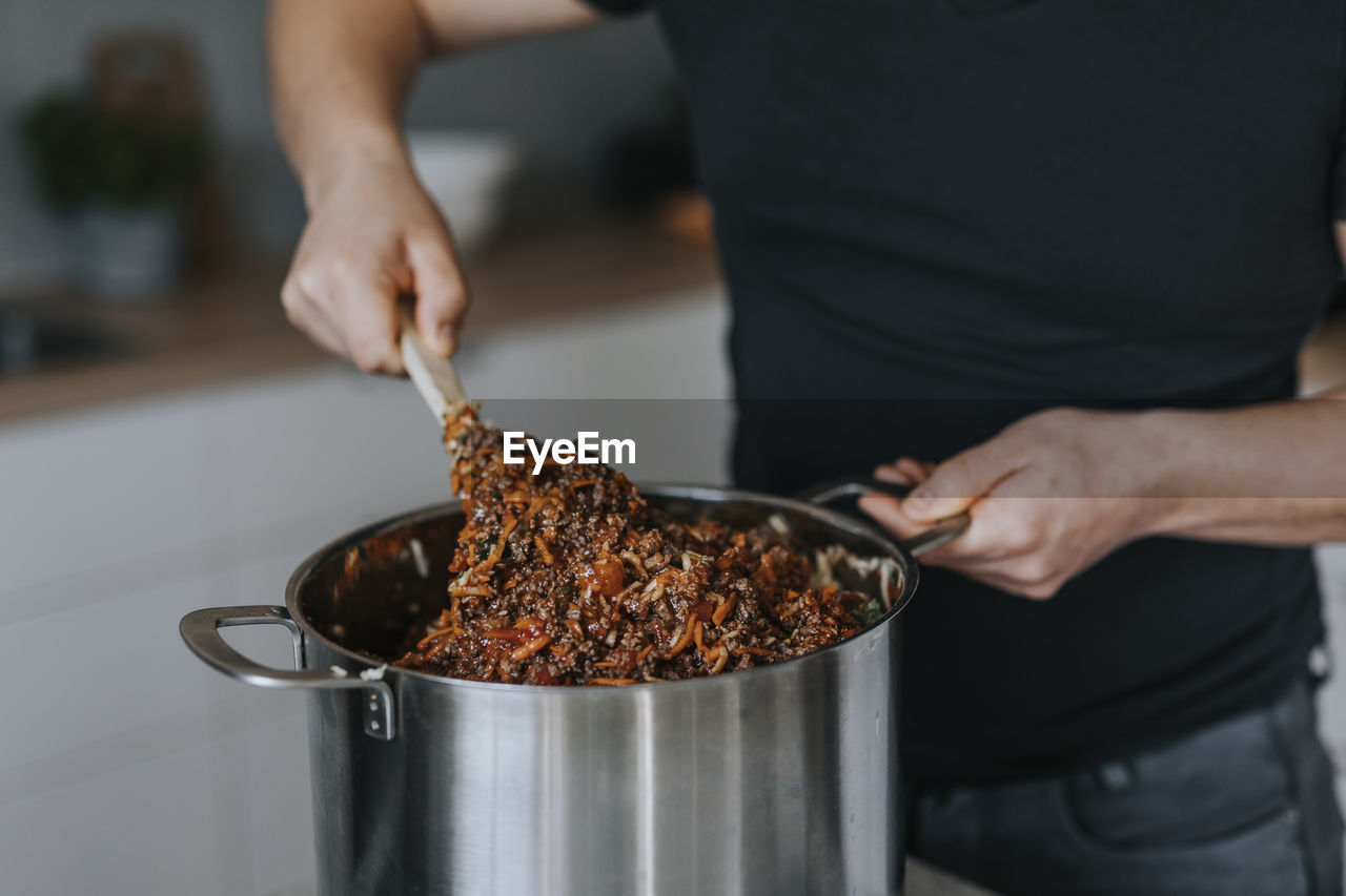 Man's hands mixing food in saucepan