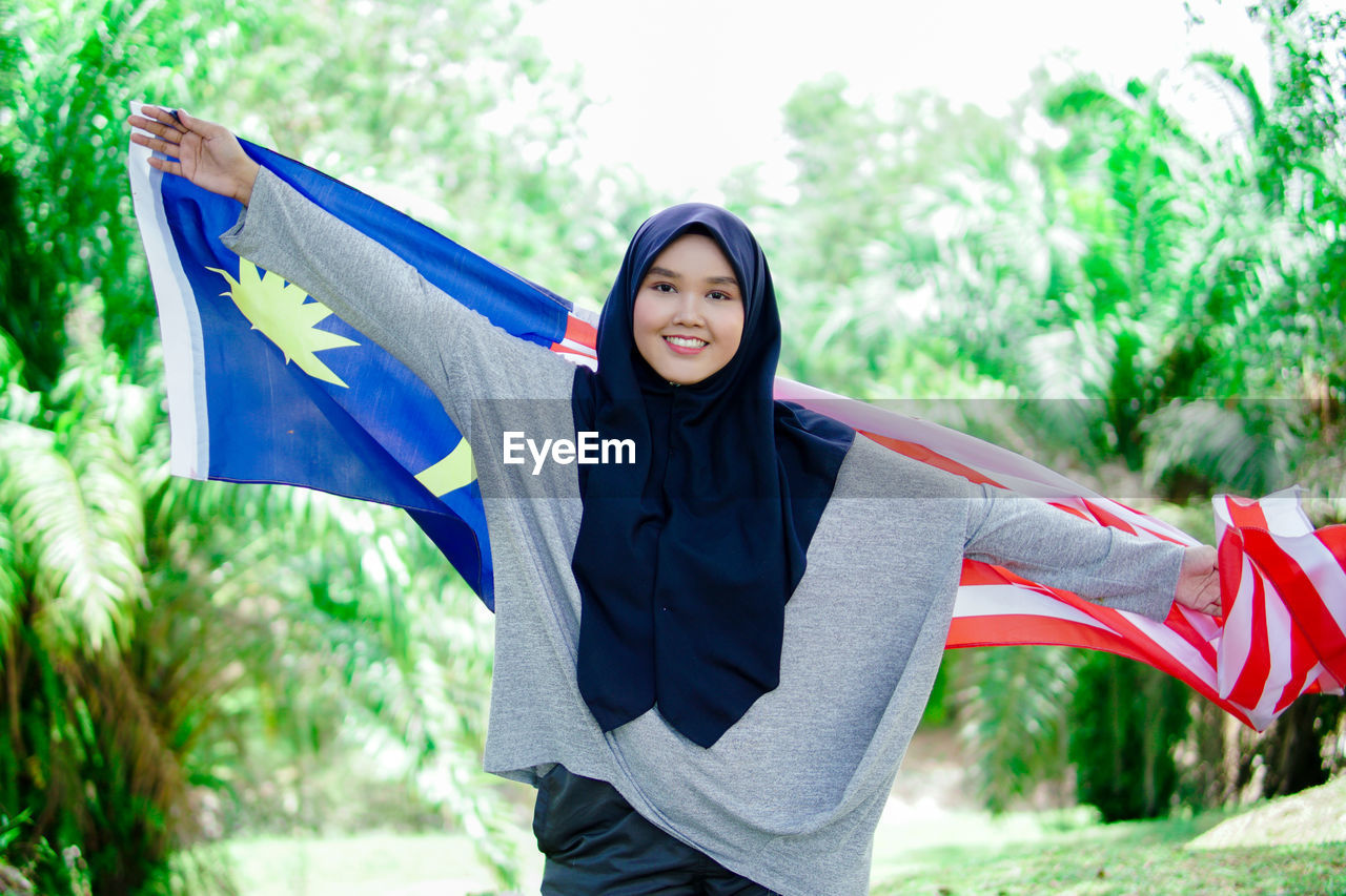 Muslim woman happy holding a malaysian flag. malaysia independence day.