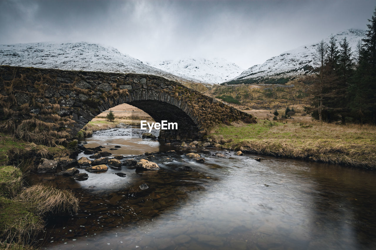 Arch bridge over river during winter