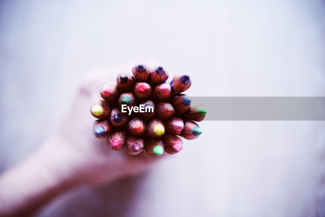 Close-up of hand holding multi colored pencils