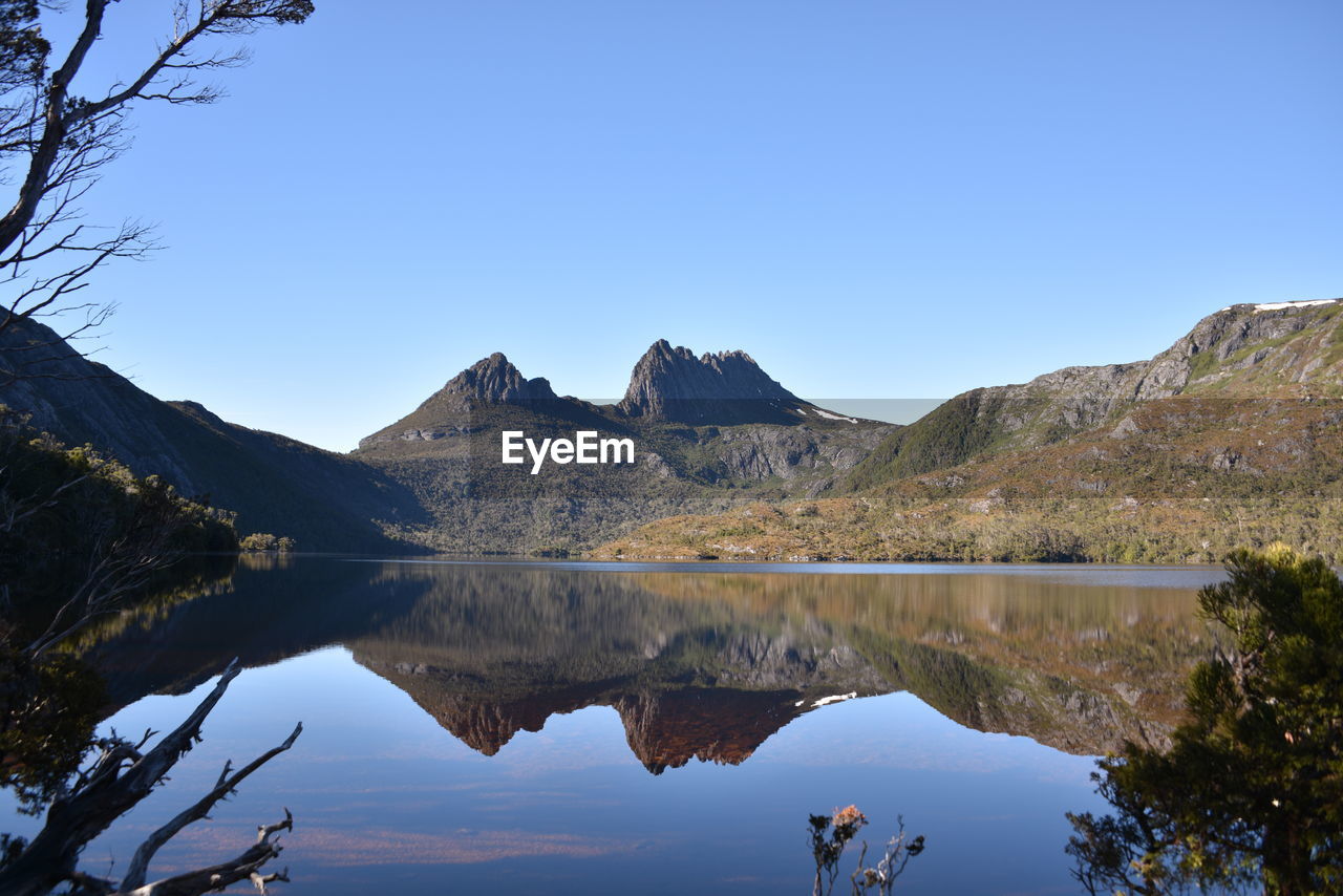 Scenic view of lake and mountains against clear blue sky