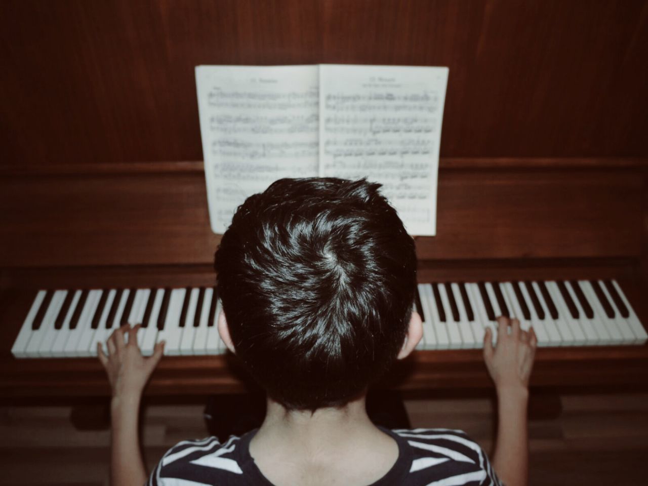 Rear view of child playing piano