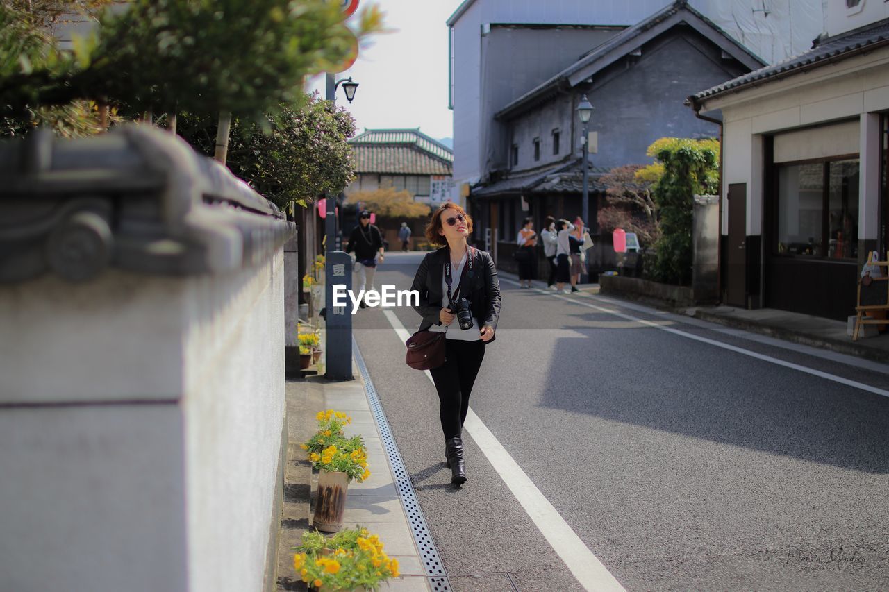 Full length of woman walking on road in city