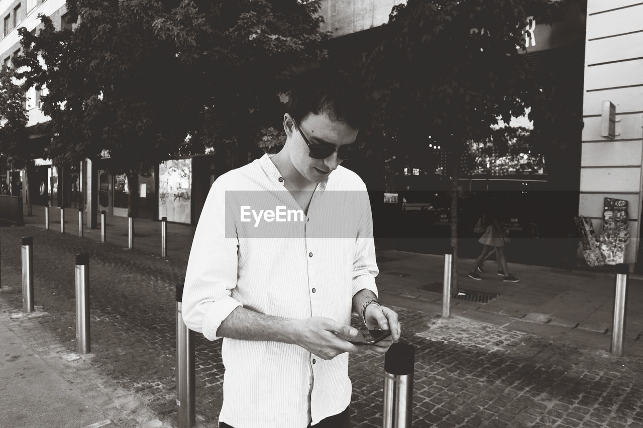 Young man using mobile phone while standing on street