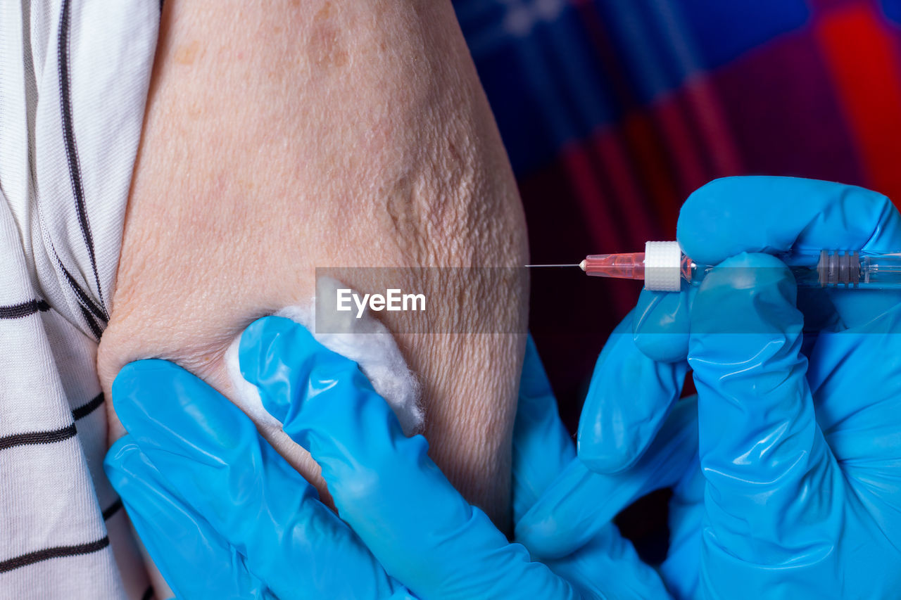 Cropped hand of doctor holding vaccinating patient