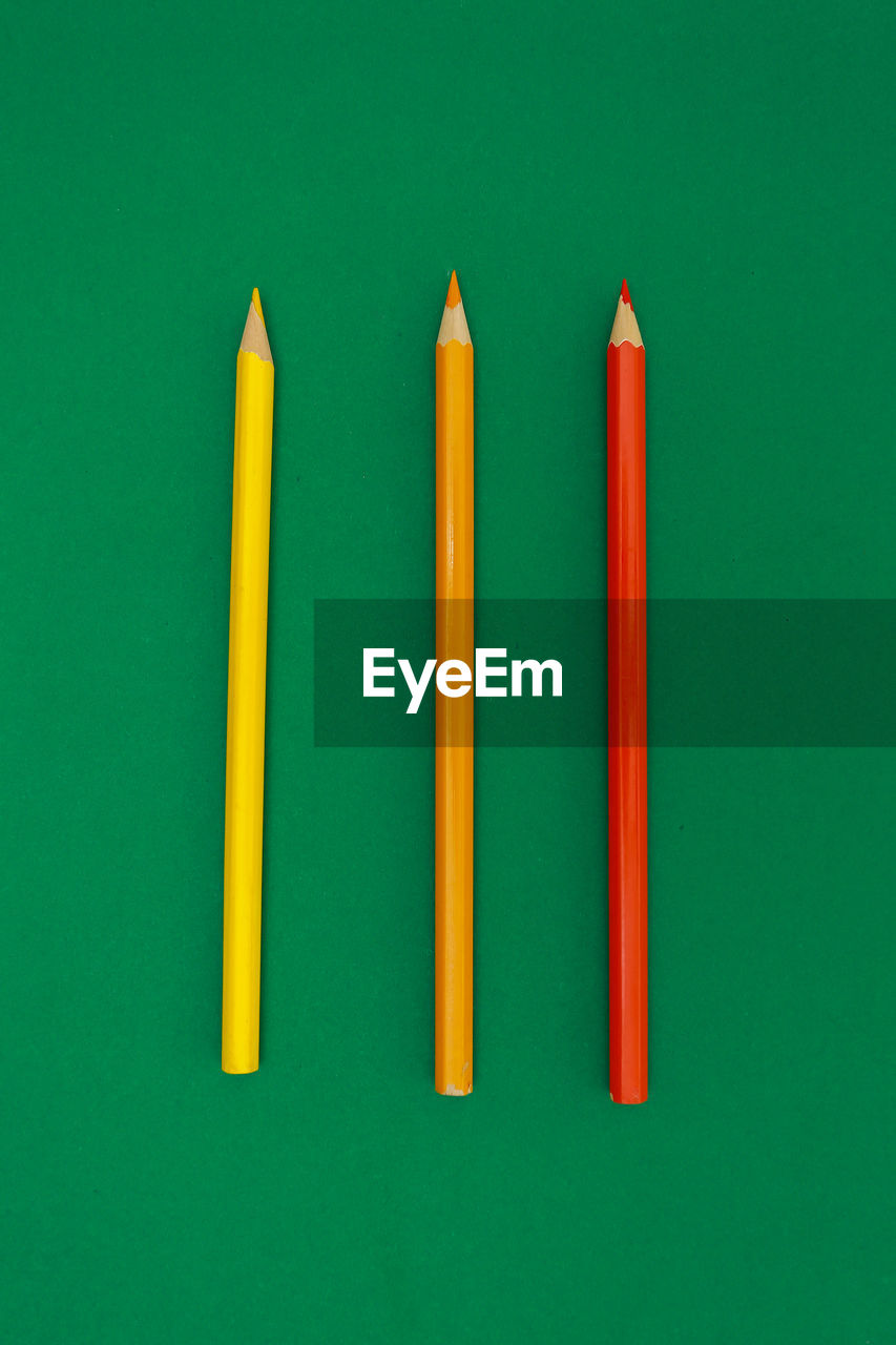 Close-up of multi colored pencils over green background