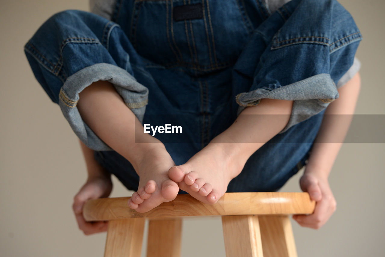 Low section of boy sitting on stool