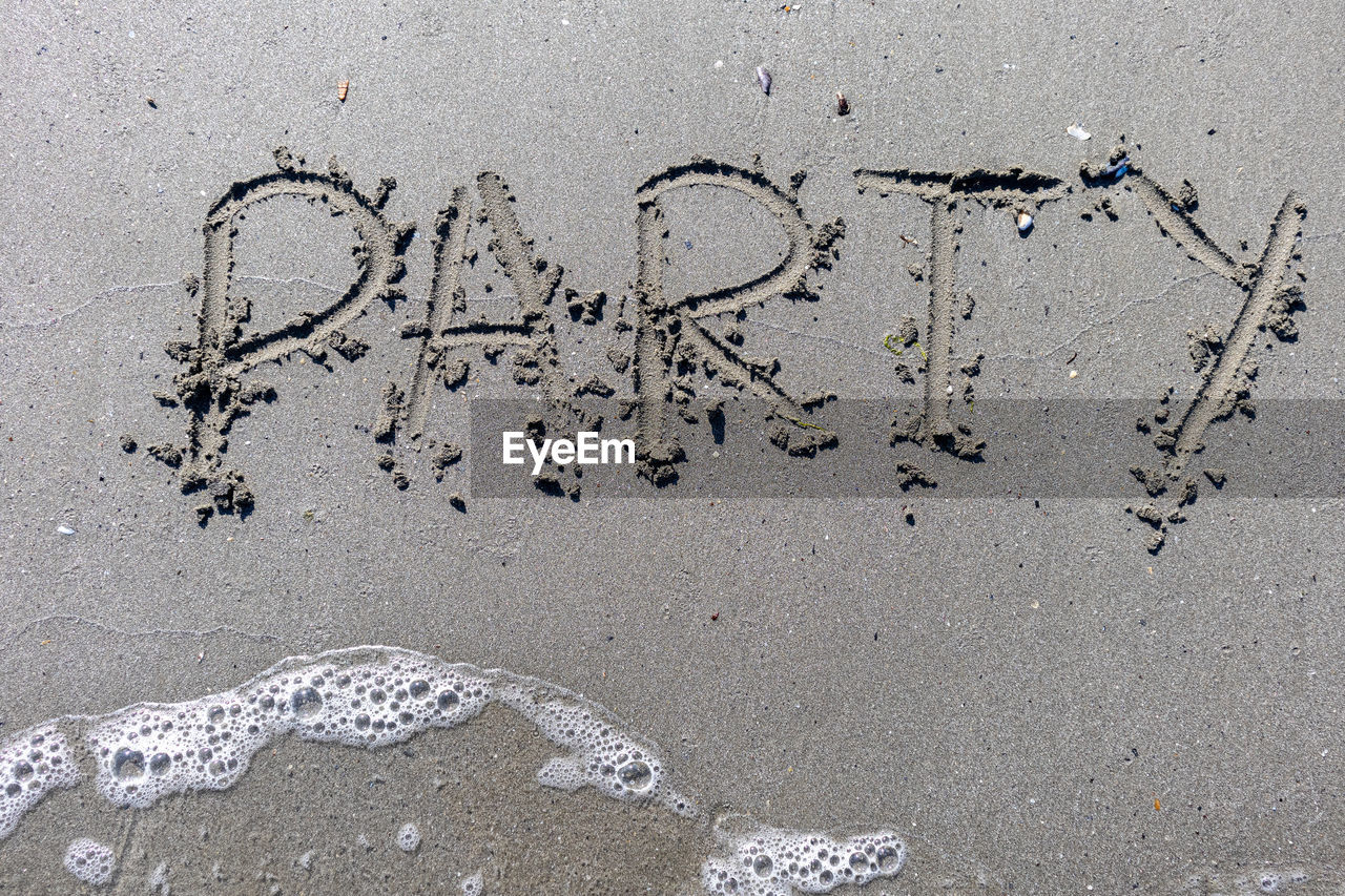 The word party written on a sandy beach