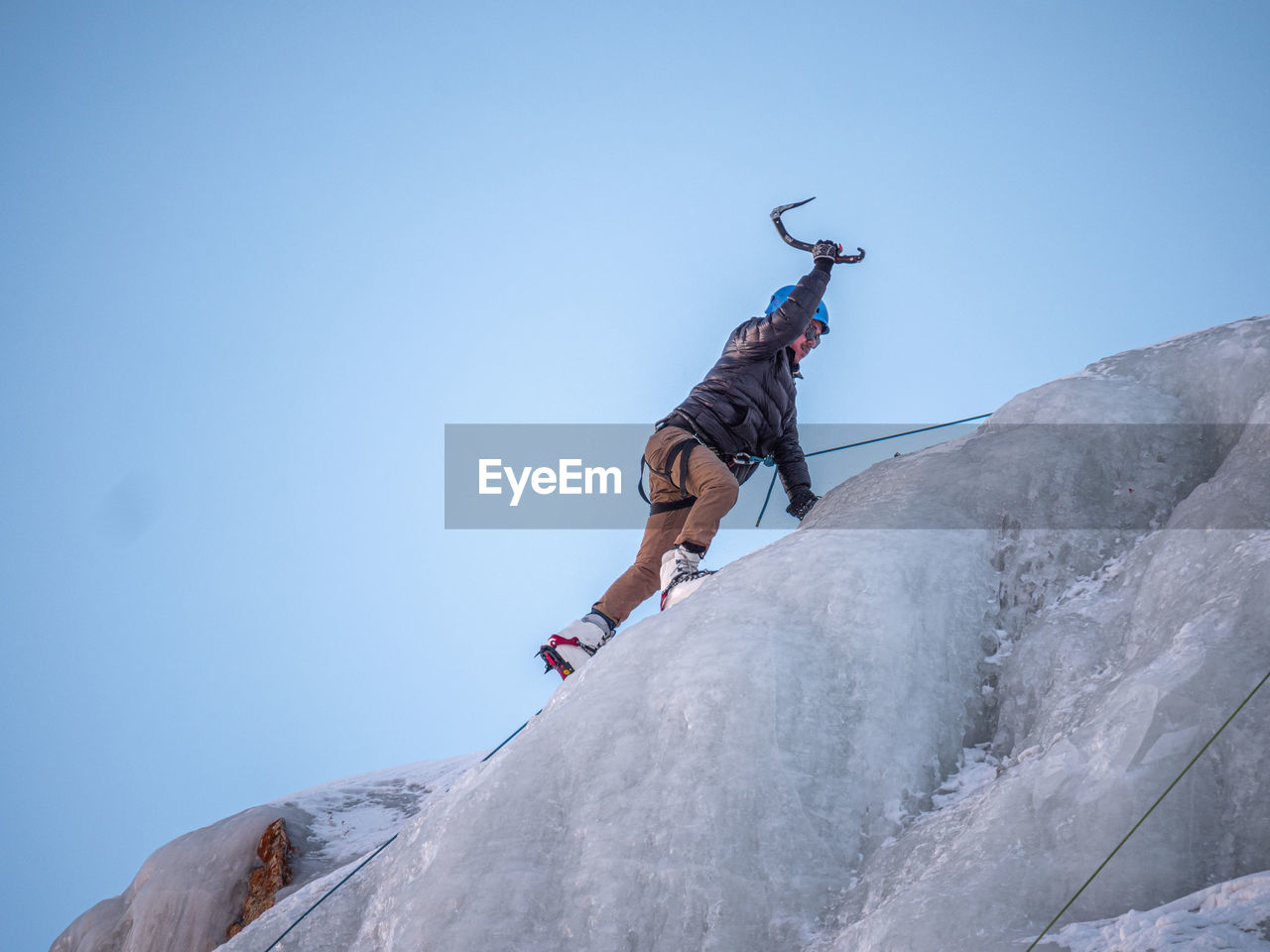 Low angle view of hiker climbing ice