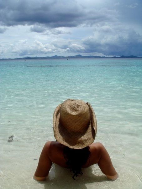Rear view of woman with beach hat sunbathing in water