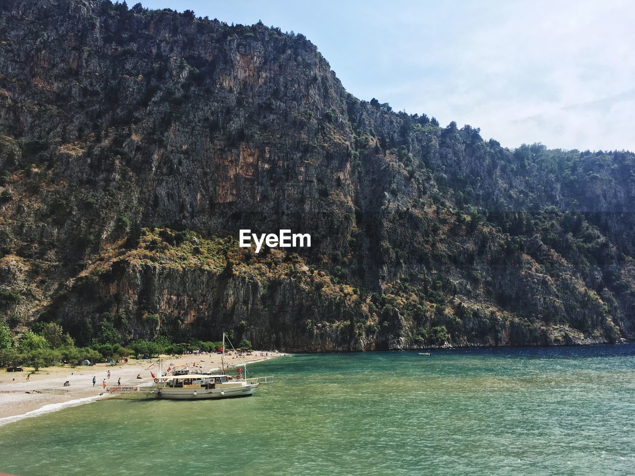 Scenic view of sea and rocky mountain against sky