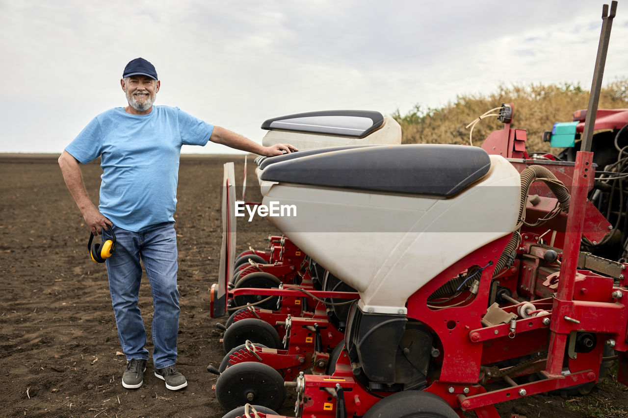 Mature male farmer standing by tractor at farm