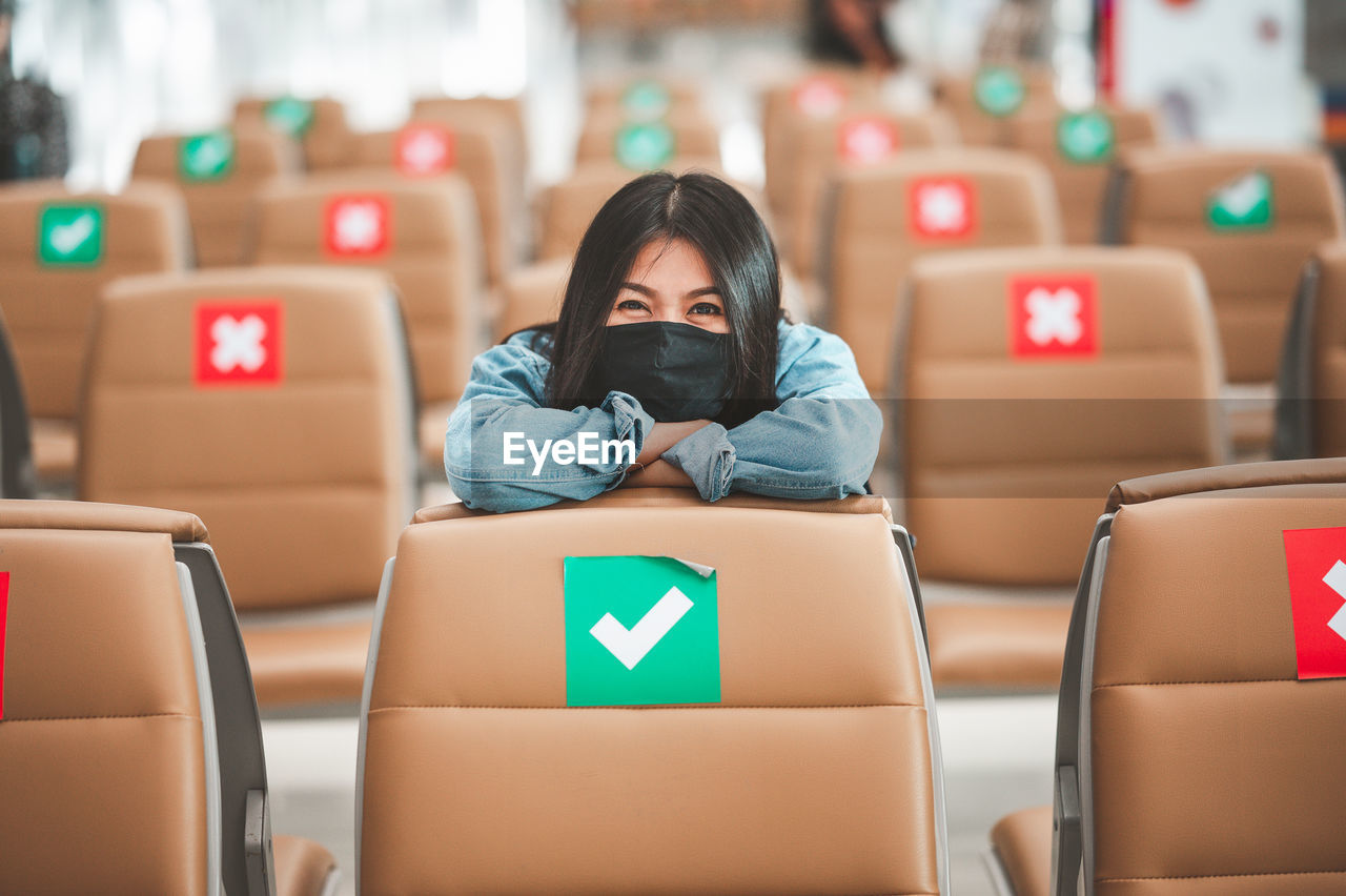 Portrait of woman wearing flu mask sitting at airport