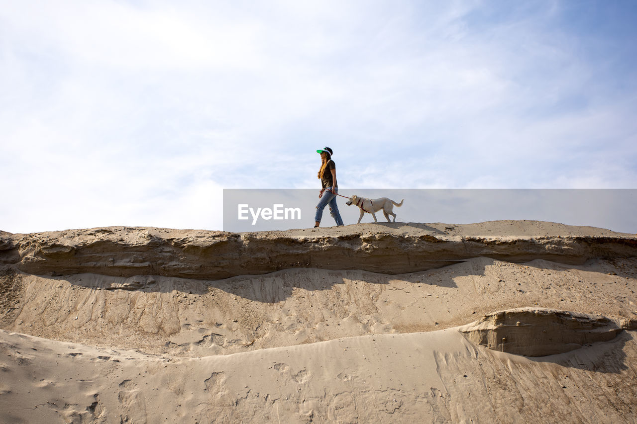 Young woman walking her dog in desert